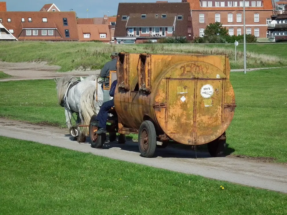 Percherón tirando del carro de recogida de basura en la isla de Juist, Alemania